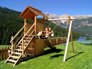 two people on a swing in a playground at Apartments Serghela in San Cassiano