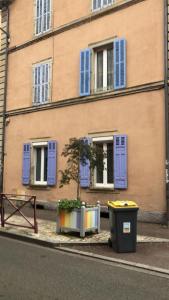 a building with blue shuttered windows and a trash can at Escale meublée in Belfort