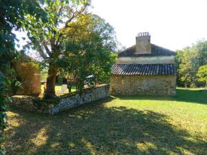 un antiguo edificio de piedra con un árbol en el patio en Comfortable holiday home with garden, en Sainte-Croix-de-Beaumont