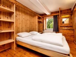 Villers-Sainte-GertrudeにあるMarvelous Holiday Home in Durbuy with Saunaの木製の壁と大型ベッドが備わるベッドルーム1室が備わります。