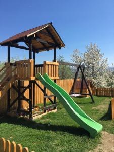 a playground with a green slide in the grass at Soare-n Maramureș in Budeşti