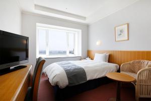 霧島市にあるホテル京セラのベッド1台、薄型テレビが備わるホテルルームです。