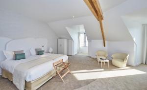 a white bedroom with a large bed and two chairs at Appartements La Cigale in Arzon