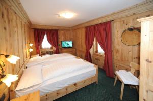 a bedroom with a large bed with red curtains at Hotel Alpina in Livigno