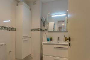 une salle de bain blanche avec un lavabo et un miroir dans l'établissement CHIQUITA PLACE, Praia da Luz, à Luz