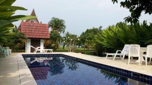 a swimming pool with white chairs and a table at Hibiscus Cottage in Ban Dan Kao