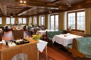 a dining room with tables and chairs and windows at SeeHotel Wassermann in Seebruck