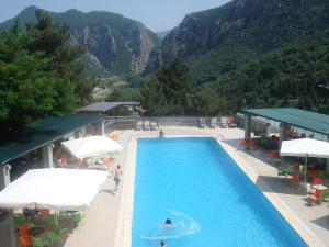una piscina con mesas y sombrillas junto a una montaña en Apolis hotel en Mouzákion