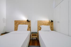 two beds in a room with white walls at Madragoa Cosy Apartment in Lisbon