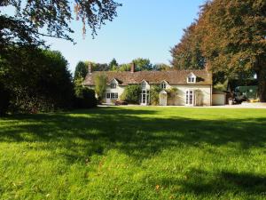 une maison avec une grande cour avec une pelouse verte dans l'établissement West Cottage, Cerne Abbas Lane, à Dorchester