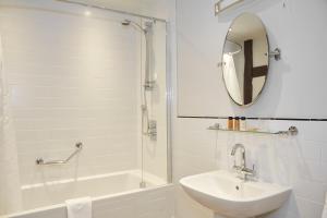 a bathroom with a sink and a shower with a mirror at White Hart Hotel by Greene King Inns in Coggeshall