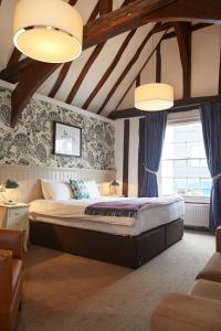 a bedroom with a large bed with blue curtains at White Hart Hotel by Greene King Inns in Coggeshall