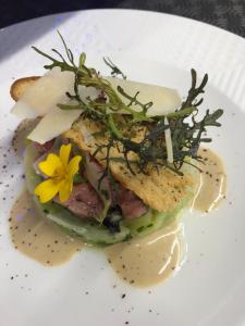 a sandwich with a yellow flower on a white plate at Hotel-Restaurant Lann Roz / Côte Cuisine in Carnac
