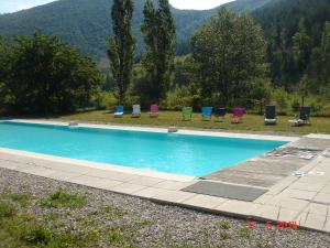 a blue swimming pool with chairs and mountains in the background at le moulin in Pradelle