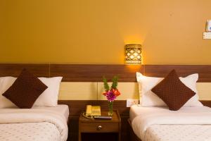 una habitación de hotel con 2 camas y una lámpara en Hotel Trip Pokhara, en Pokhara