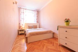 a small bedroom with a bed and a dresser at Rental Apartments Szeroki Dunaj in Warsaw
