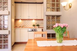 a vase of pink flowers sitting on a table in a kitchen at Rental Apartments Szeroki Dunaj in Warsaw
