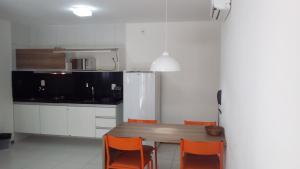 a kitchen with a wooden table and orange chairs at Apartamento Iloa Residence in Barra de São Miguel