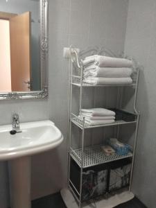 a bathroom with a sink and a shelf with towels at Apartamento Conde Luna in León