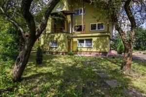 una casa amarilla con dos árboles delante de ella en Parkowa House, en Cracovia