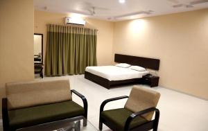 ein Schlafzimmer mit einem Bett und zwei Stühlen darin in der Unterkunft Hotel Varenya Inn in Yavatmāl