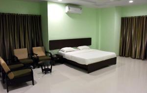 ein Schlafzimmer mit einem Bett, einem Sofa und einem Stuhl in der Unterkunft Hotel Varenya Inn in Yavatmāl