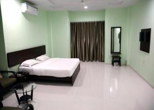 ein Schlafzimmer mit einem Bett, einem Stuhl und einem Spiegel in der Unterkunft Hotel Varenya Inn in Yavatmāl