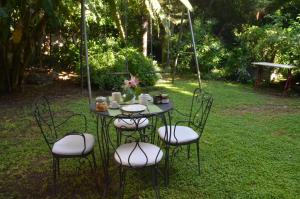 ein Tisch mit vier Stühlen und ein Tisch mit Blumen darauf in der Unterkunft Il Giardino di Caronda in Catania