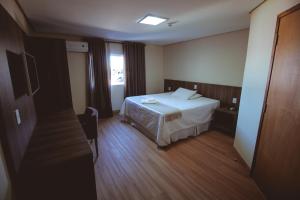 a hotel room with a bed and a window at Rota Hotéis Mineiros in Mineiros +30 photos