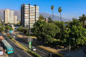 a city street with cars and a tall building at Hotel Plaza Ñuñoa in Santiago