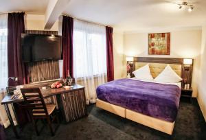 ein Hotelzimmer mit einem lila Bett und einem Schreibtisch in der Unterkunft Hotel Famosa in Düsseldorf