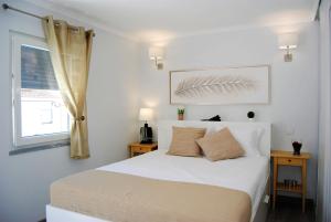 a bedroom with a white bed and a window at Casa Lusitana da Baia in Porto Covo