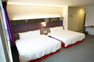 two beds in a hotel room with white sheets at Yily House怡家居 in Yilan City