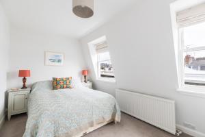 a white bedroom with a bed and two windows at JOIVY Cosy 1 bed flat with balcony in Pimlico, next to Warwick Square in London