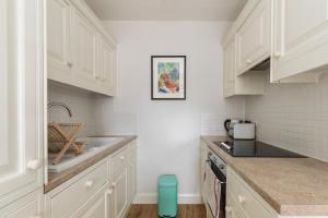 a kitchen with white cabinets and a sink at JOIVY Cosy 1 bed flat with balcony in Pimlico, next to Warwick Square in London