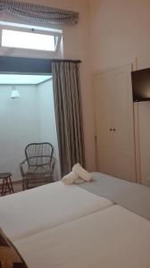 1 dormitorio con 1 cama blanca grande y ventana en Casa Boutique La Pila del Pato, en Sevilla
