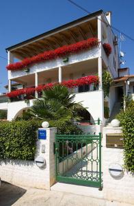 een gebouw met rode bloemen en een groene poort bij Apartments Šorić in Rovinj