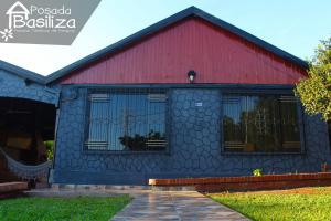 a blue and red house with a red roof at Posada Basiliza, Encarnación PY in Encarnación