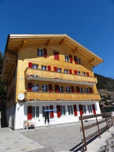 a large wooden building with a man standing in front of it at Chalet Schönbühl in Mürren