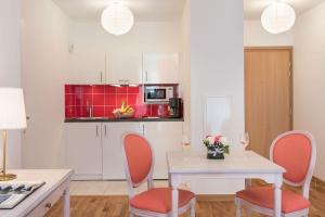 une cuisine avec une table blanche, des chaises et des armoires rouges dans l'établissement Villa Médicis Trouville-sur-mer, à Trouville-sur-Mer