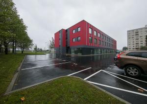 a red building in a parking lot in the rain at LKS Apartment one in Tallinn