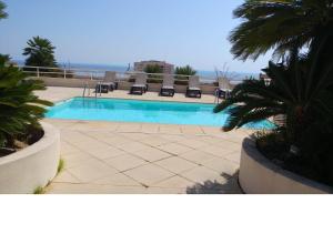 a swimming pool with chairs and the ocean in the background at Apartment Monaco Palais Josephine in Beausoleil