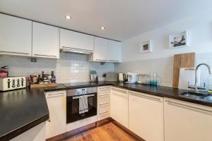 a kitchen with white cabinets and a black stove top oven at Lovely 2 bedroom flat in Chelsea, sleeps 4 in London
