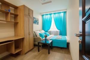 a small bedroom with a blue bed and a window at Five Stars Perfect Comfort in Krasnoyarsk