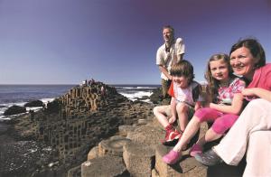 a family sitting on the rocks at the beach at Causeway Coast Apartment in Ballycastle