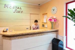 a man standing behind a reception counter in a hotel room at Hostal Viky in Madrid