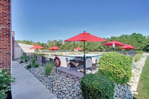 a patio with tables and red umbrellas and a pool at Blue Creek Inn in Waretown
