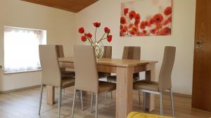 a dining room table with chairs and a vase with red flowers at ELENA flat Mohn Duisburg Zentrum in Duisburg