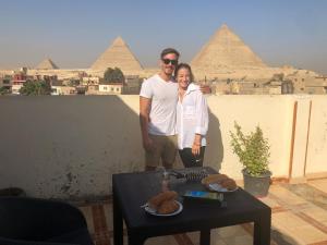 un hombre y una mujer parados frente a las pirámides en Pyramids Family Inn, en El Cairo