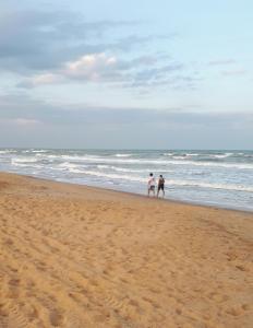 dos personas caminando por la playa cerca del océano en Casa em Unamar,Cabo Frio,à 200m da praia,em condomínio com segurança 24 hs, en Cabo Frío